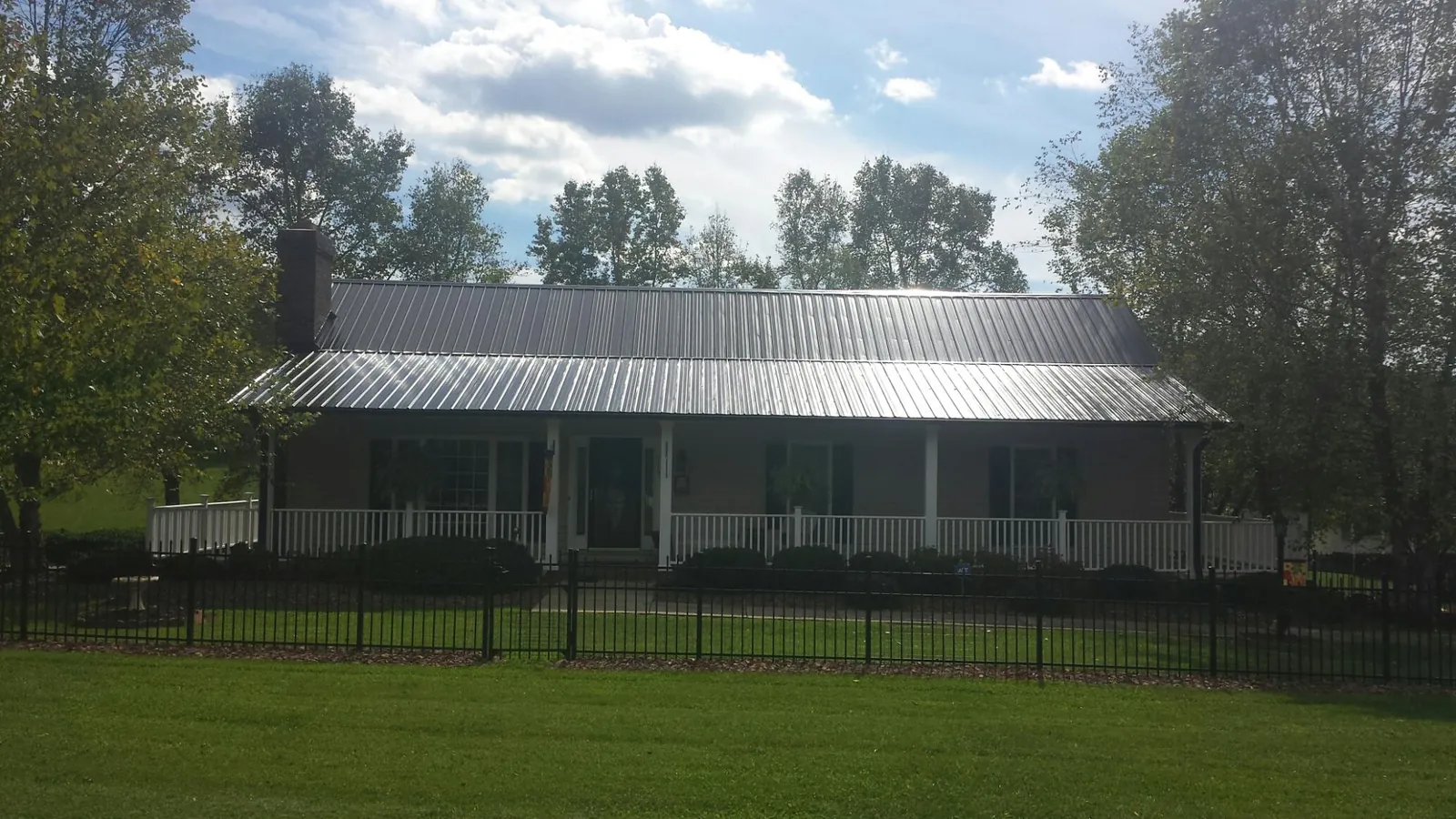 Gray metal roof on a brick ranch with a full width front porch — Gutter Guard Installation work by our crew in Mulberry
